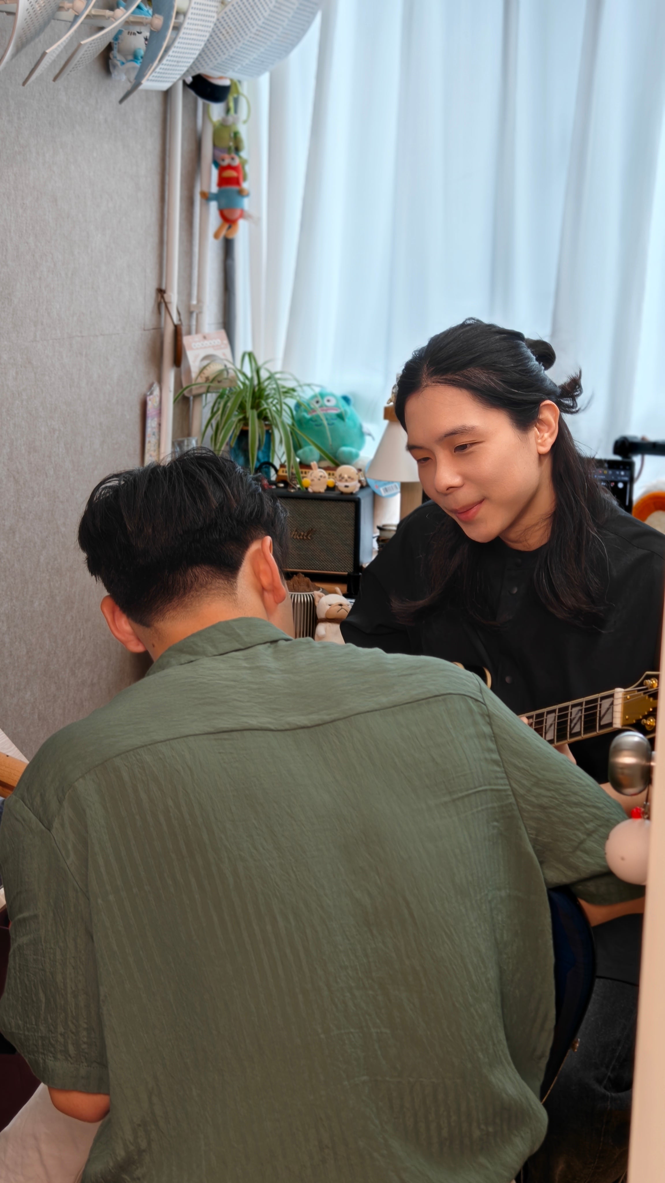 Two people sitting together having guitar lesson in Tritone Music