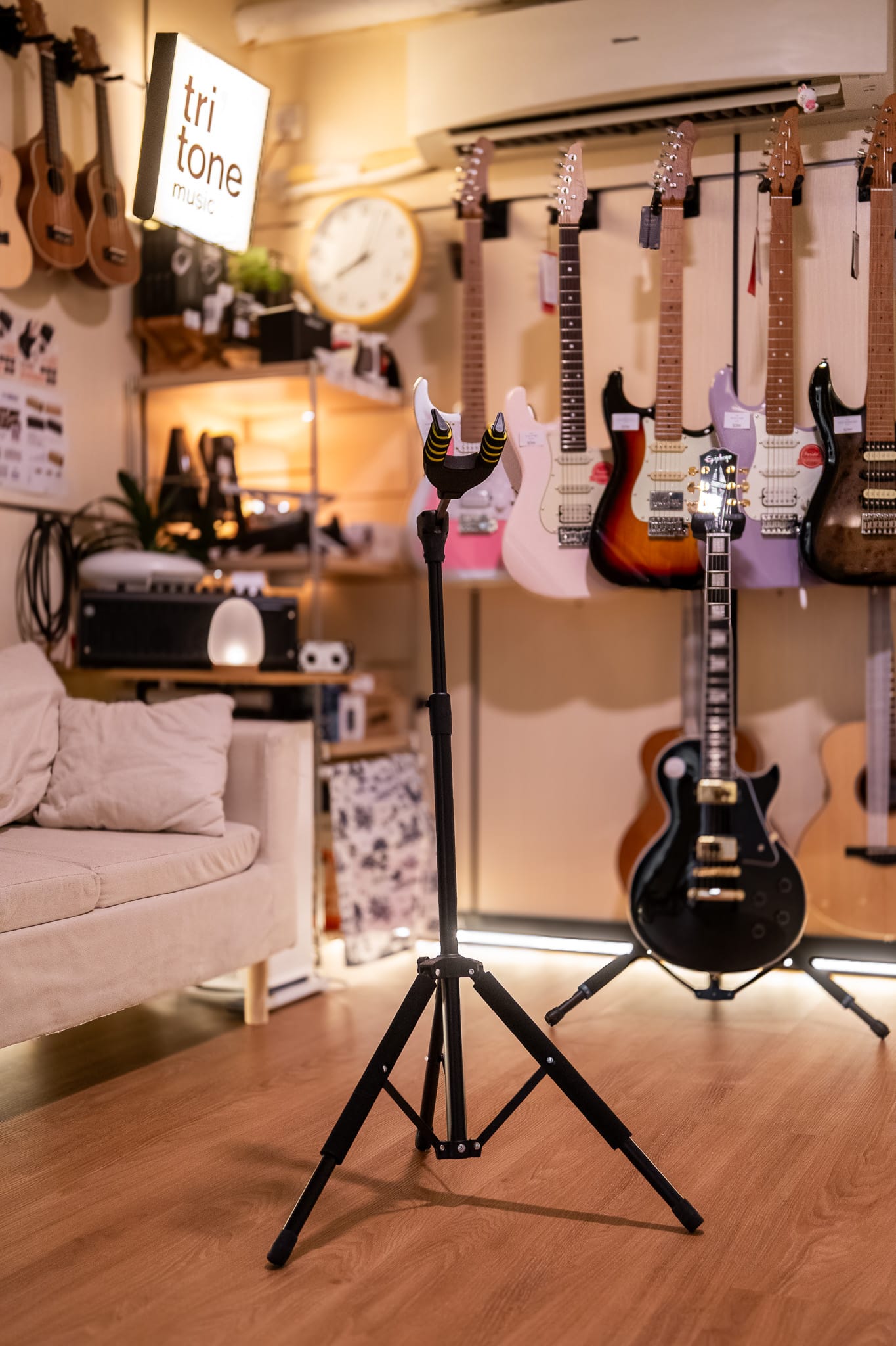 Guitar stand in a music store with guitars hanging on the wall