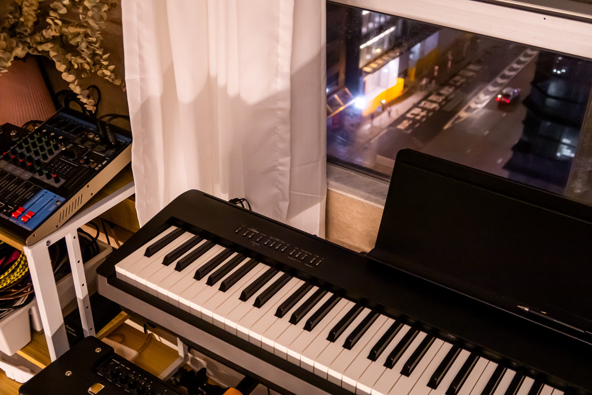 Keyboard in a room with a cityscape on a screen in the background Tritone Music 駿通音樂 租電子琴 租Band房 電子琴房