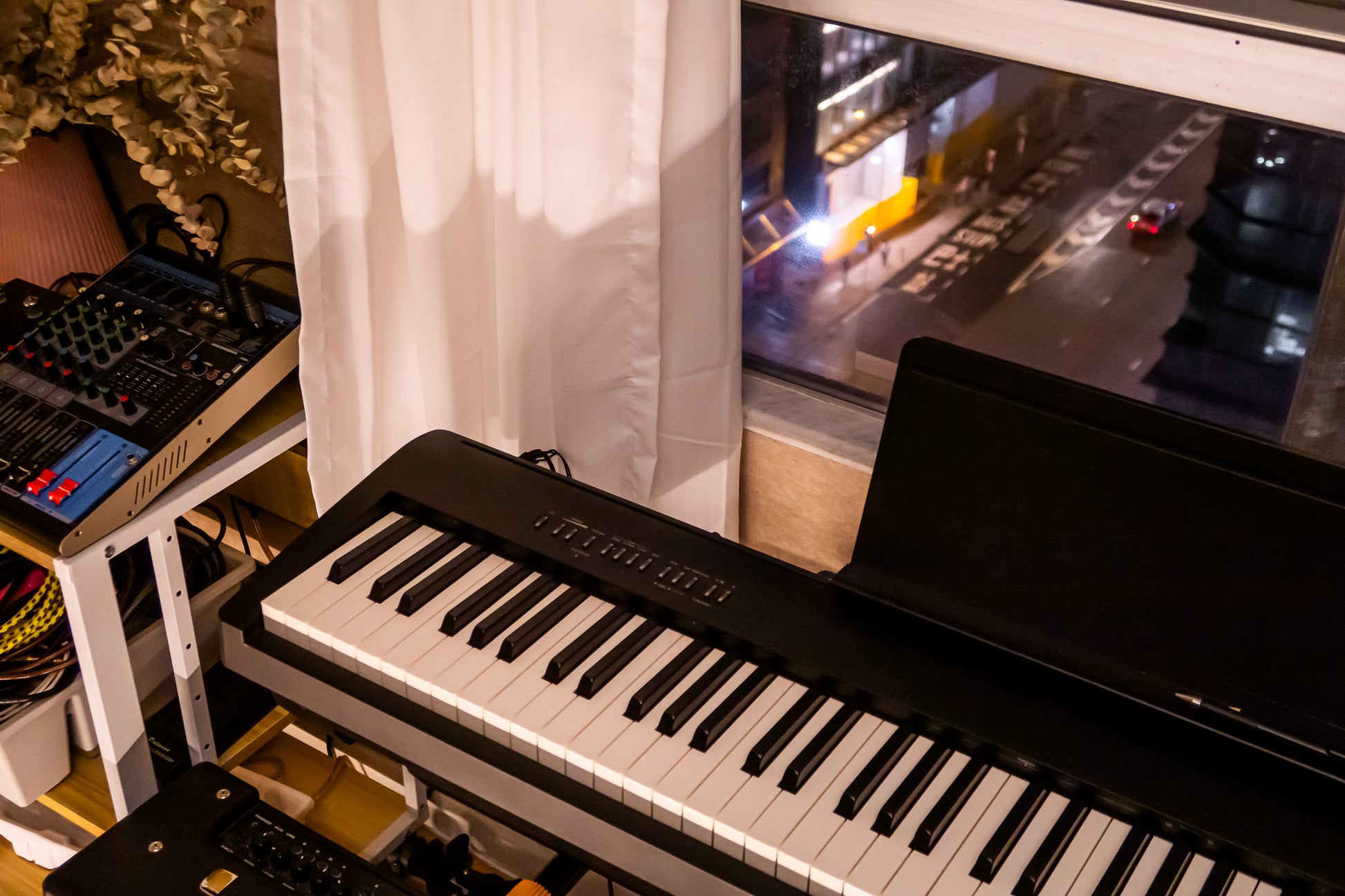 Keyboard in a room with a cityscape on a screen in the background Tritone Music 駿通音樂 租電子琴 租Band房 電子琴房