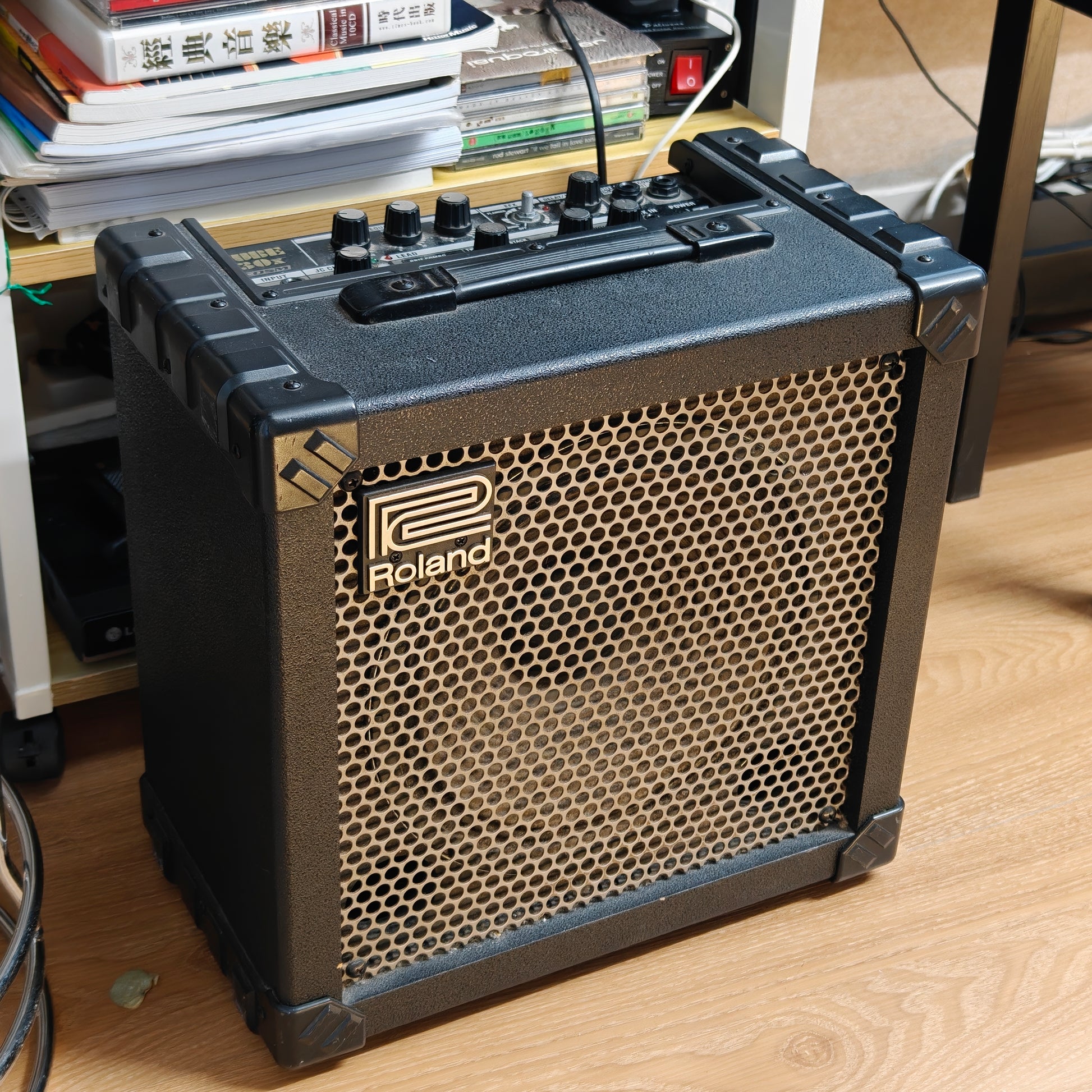 Roland amplifier for rent at Tritone Music on a wooden surface with books in the background